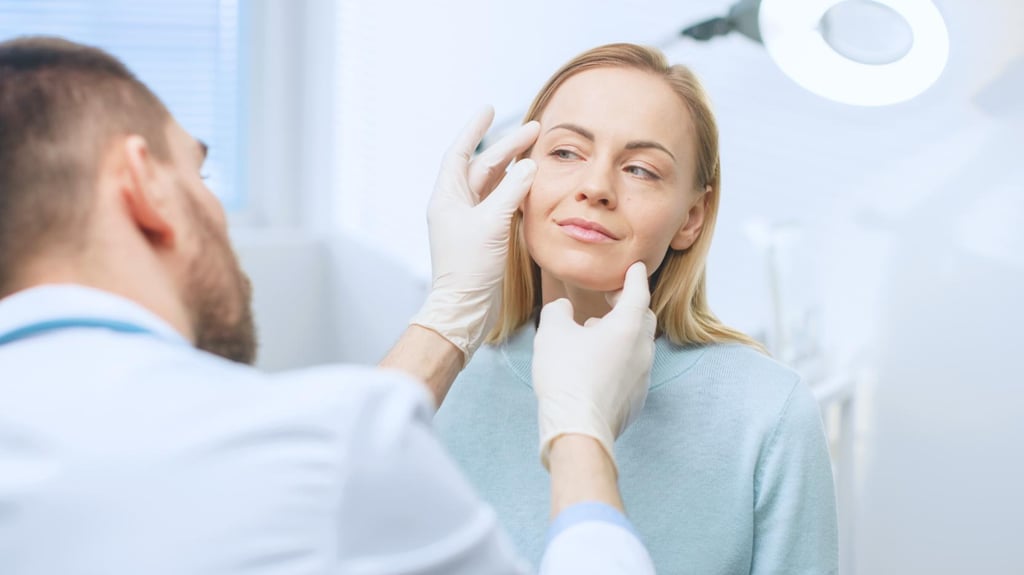 Doctor examining woman’s face during aesthetic consultation in medical office