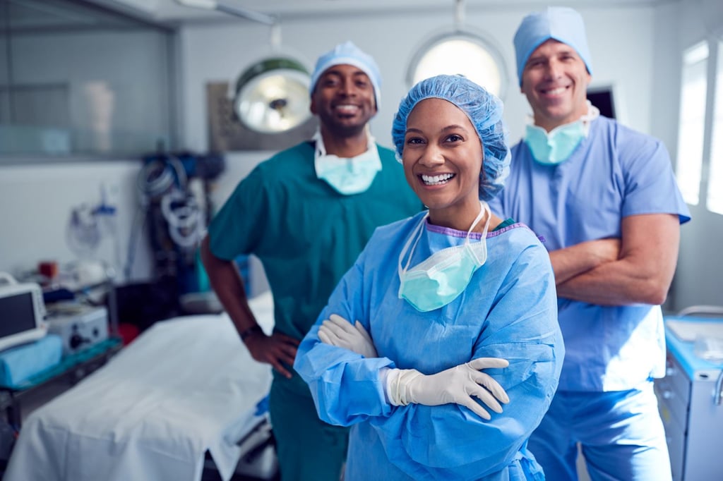 Three medical professionals in surgical attire standing together inside operating room
