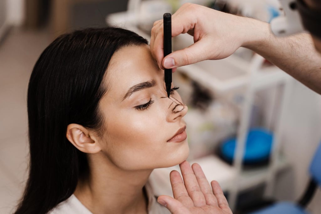 Doctor marking woman’s nose during rhinoplasty consultation in aesthetic clinic