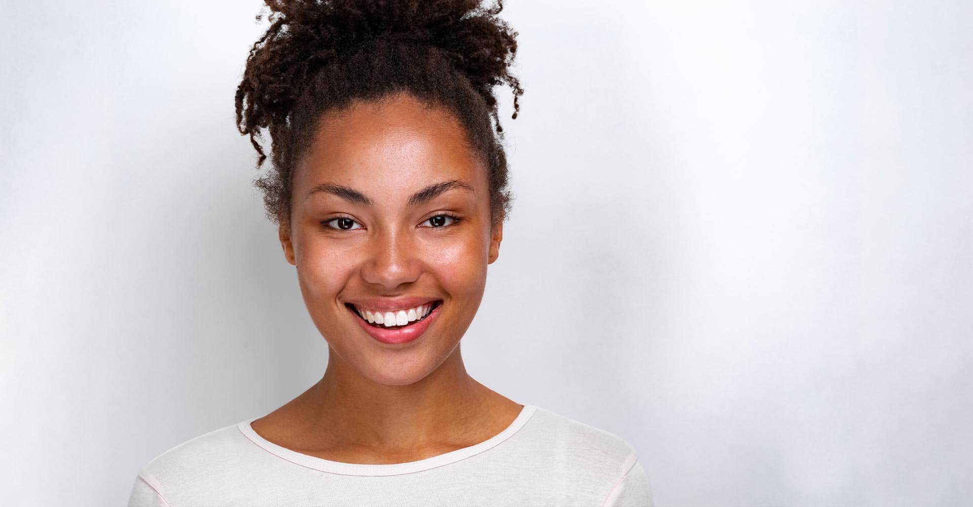 Closeup portrait of a cheerful mulatto girl over light studio background- Image