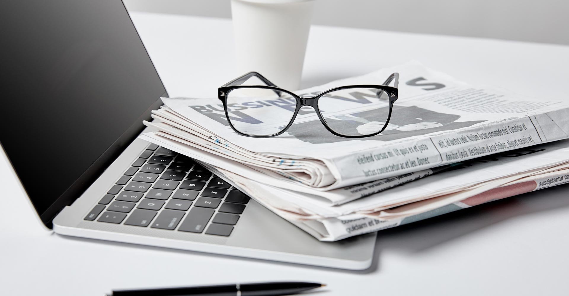 Selective focus of laptop with blank screen near business newspapers