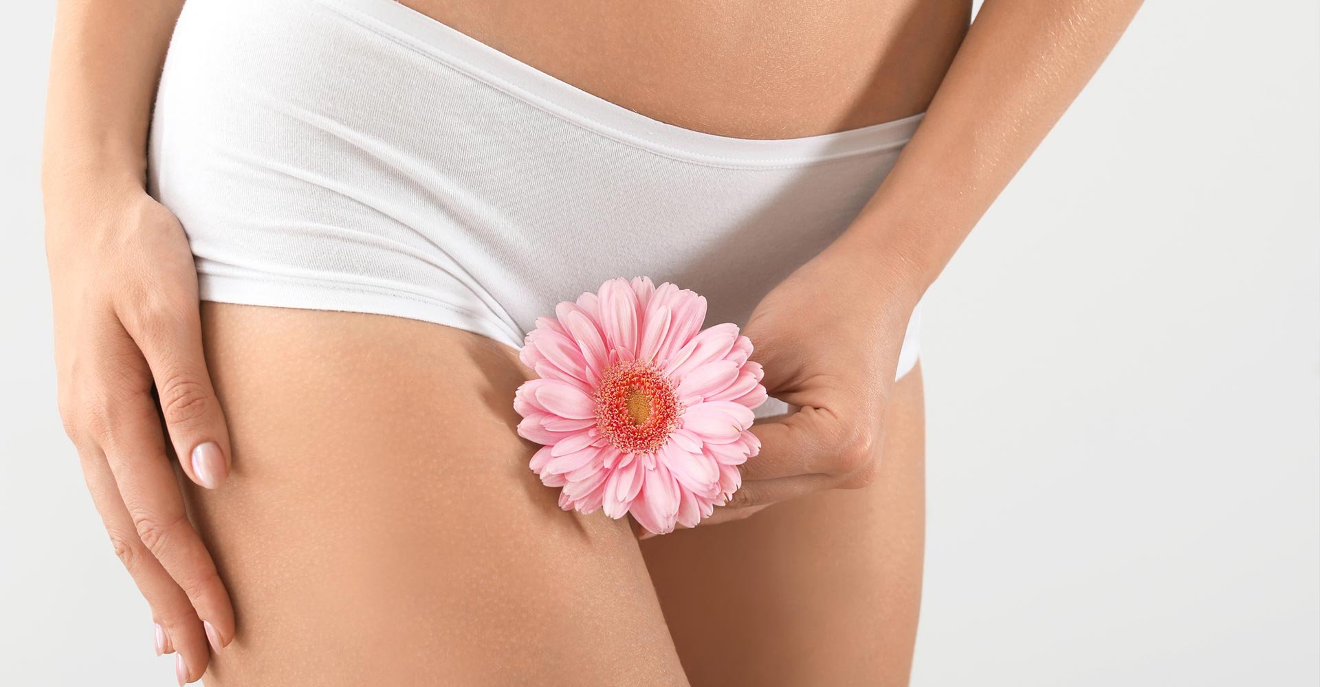 Young woman with flower on grey background, closeup. Gynecology concept